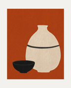Bottle Hour cream bottle wall art, pale vessel beside low black bowl on terracotta background