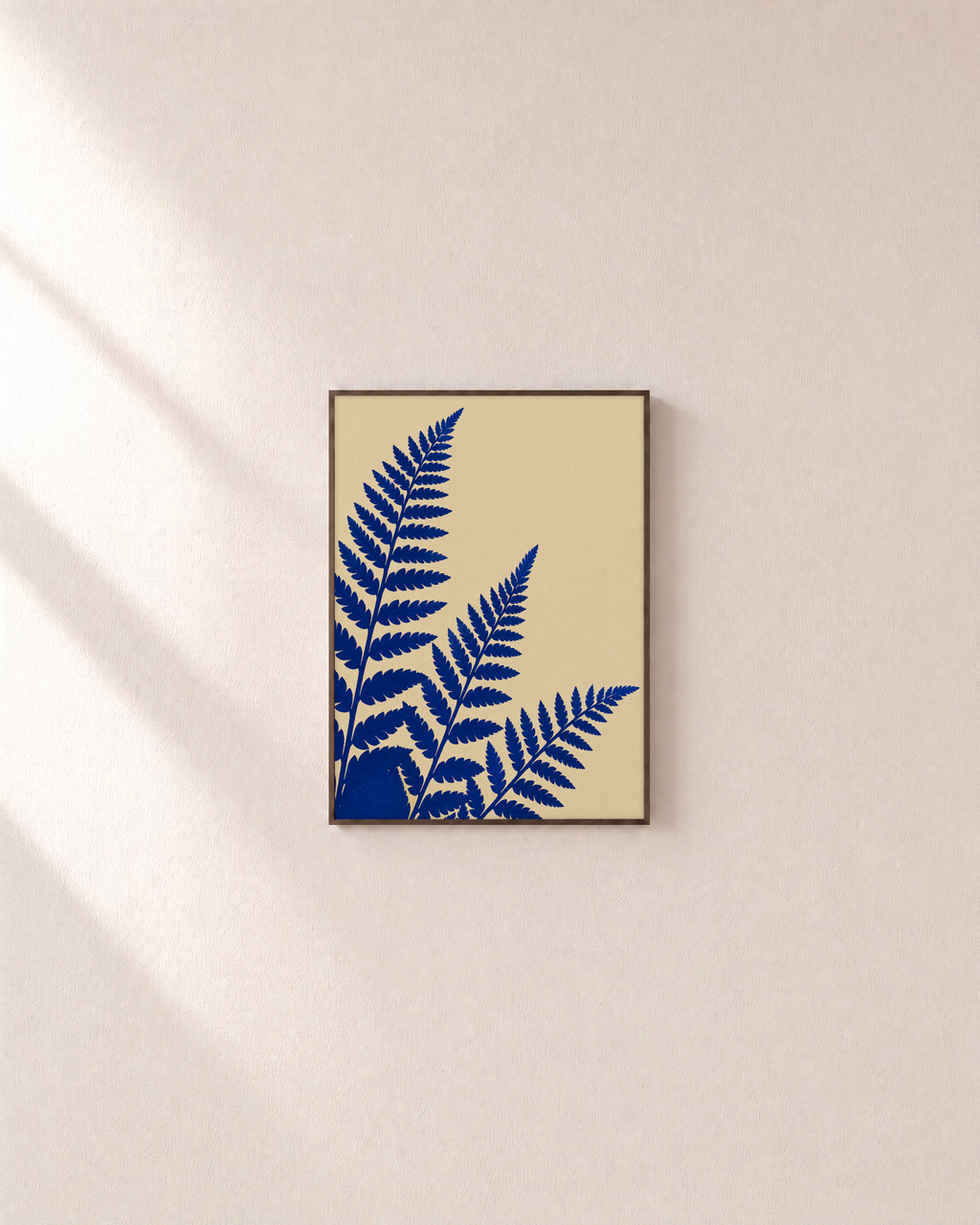 Three Fern Cuts Cobalt unframed print is shown framed for styling in a plain wall; frame not included