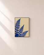Three Fern Cuts Cobalt unframed print is shown framed for styling in a plain wall; frame not included