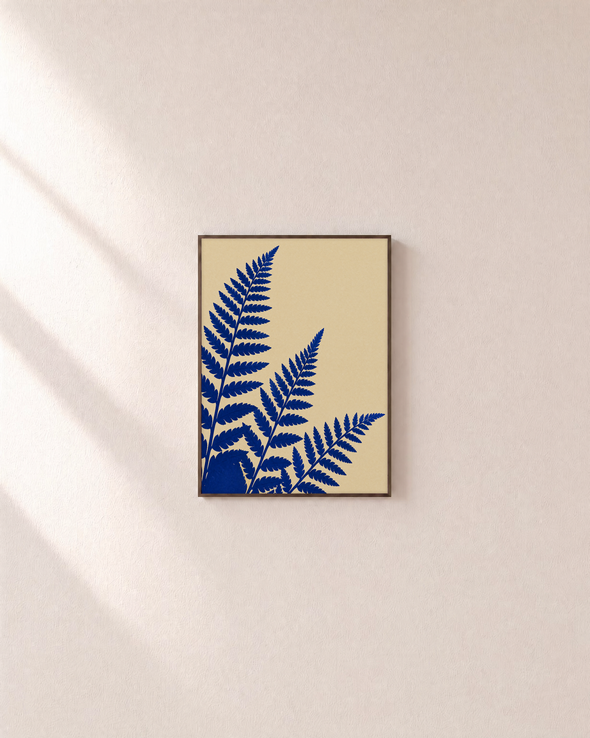 Three Fern Cuts Cobalt unframed print is shown framed for styling in a plain wall; frame not included