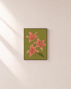 Three Coral Spotted Lilies One Olive Leaf Blade unframed print is shown framed for styling in a plain wall; frame not included