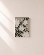 Uneven Magnolias white magnolia wall art: unframed print is shown framed for styling on a plain wall; frame not included