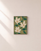 Three Magnolias On Olive Field unframed print is shown framed for styling in a plain wall; frame not included
