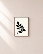 Black Leaf Sprig unframed print is shown framed for styling in a plain wall; frame not included