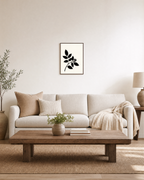 Black Leaf Sprig unframed print is shown framed for styling in a living room; frame not included