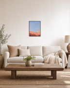 Coral Dune Below Blue Sky blue and coral abstract wall art print: unframed print is shown framed for styling in a living room; frame not included