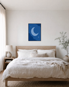 Crescent Moon with Two Stars crescent moon and stars wall art print: unframed print is shown framed for styling in a bedroom; frame not included