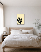 Black Leaf Sprig unframed print is shown framed for styling in a bedroom; frame not included