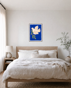 Dove Branch Blue unframed print is shown framed for styling in a bedroom; frame not included