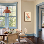 Blue Bloom Chaperone coral lily spray wall art: unframed print is shown framed for styling in a bay window dining room; frame not included