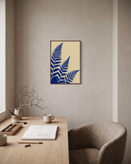 Three Fern Cuts Cobalt unframed print is shown framed for styling in a home office; frame not included