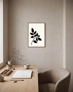 Black Leaf Sprig unframed print is shown framed for styling in a home office; frame not included