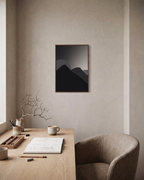 Black Peaks with Pale Sun minimalist mountain silhouette wall art print: unframed print is shown framed for styling in a home office; frame not included